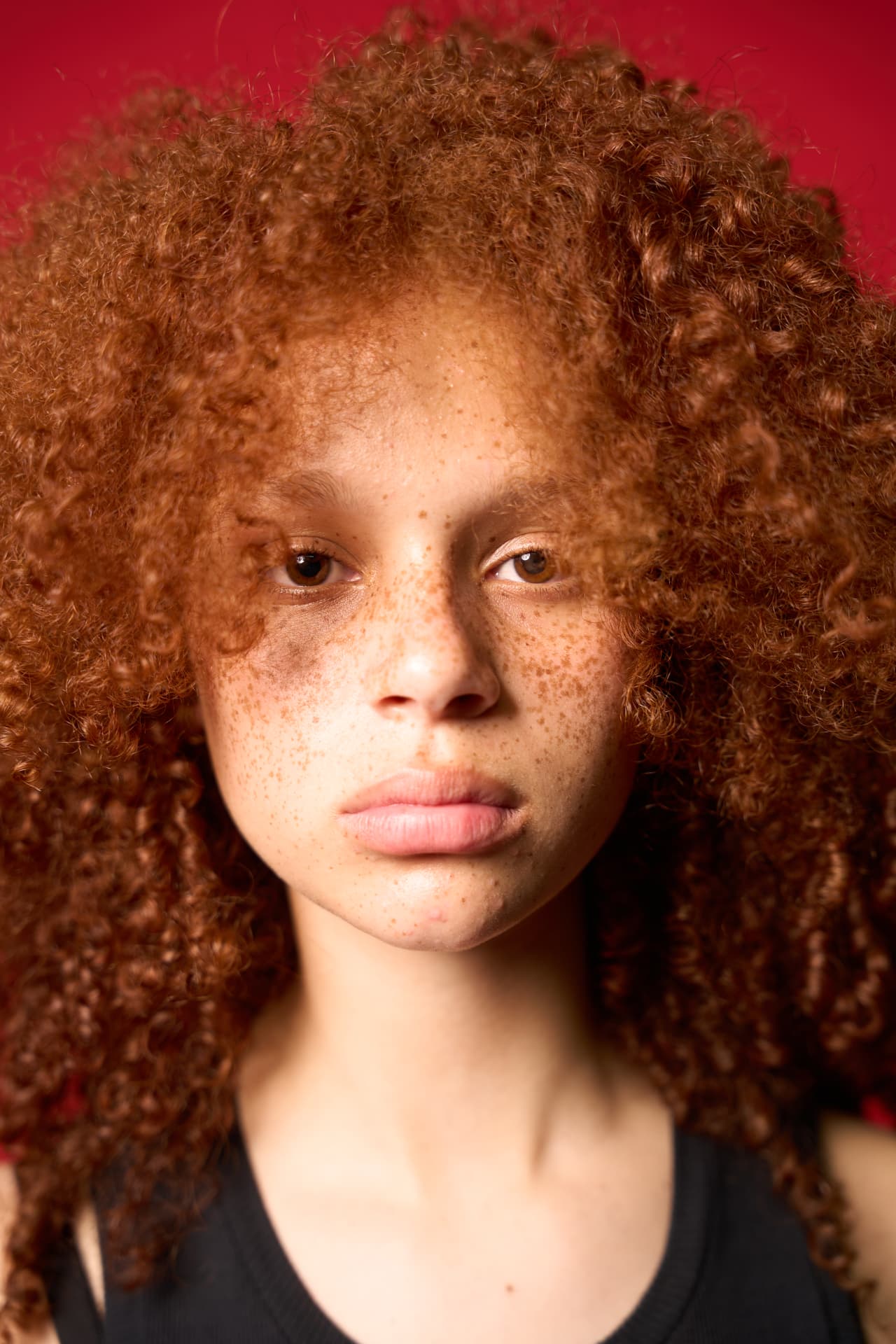 Black and white editorial portrait of a model with distinctive curls